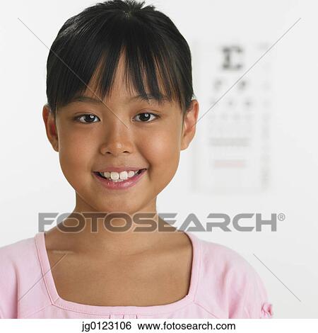 Young girl smiling with eye chart in background View Large Photo Image Stock Photograph - Young girl smiling with eye chart in background. Fotosearch