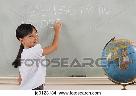 Young girl writing on blackboard View Large Photo Image Picture - Young girl writing on blackboard. Fotosearch