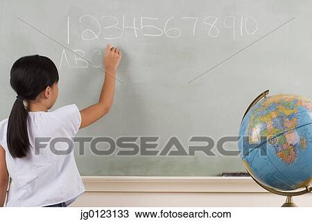 Stock Image - Young girl writing on blackboard. Fotosearch