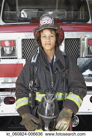 Stock Photograph - African female firefighter in front of fire truck. Fotosearch
