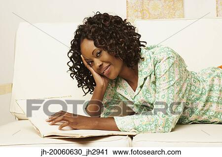 African woman laying on sofa with book View Large Photo Image Stock Image - African woman laying on sofa with book. Fotosearch