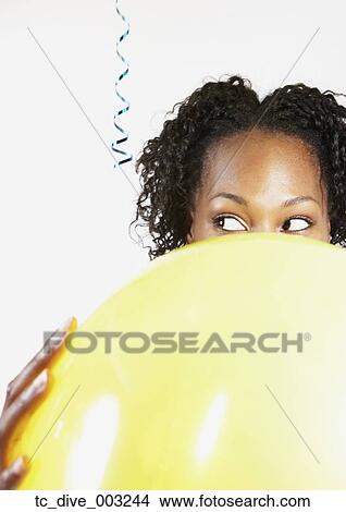 Picture - African woman looking sideways over balloon. Fotosearch