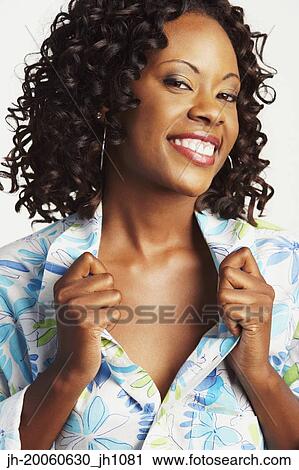 Stock Image - African woman smiling and holding shirt lapels open. Fotosearch