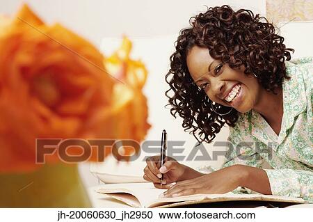 African woman smiling and writing in book View Large Photo Image Stock Image - African woman smiling and writing in book. Fotosearch