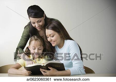 Stock Photography of Hispanic mother and two daughters reading bible ...