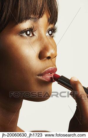 Close up of African woman applying lipstick View Large Photo Image Stock Image - Close up of African woman applying lipstick. Fotosearch