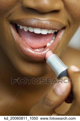 Close up of African woman applying lipstick View Large Photo Image Stock Image - Close up of African woman applying lipstick. Fotosearch