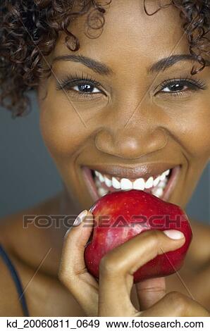 Close up of African woman eating apple View Large Photo Image Stock Photo - Close up of African woman eating apple. Fotosearch