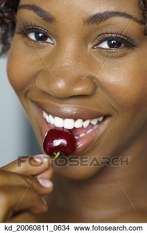 Close up of African woman eating cherry View Large Photo Image Picture - Close up of African woman eating cherry . Fotosearch