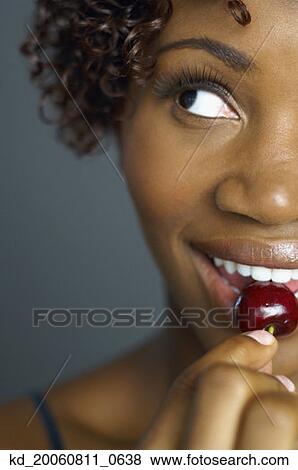 Stock Photo - Close up of African woman eating cherry . Fotosearch