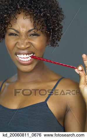 Stock Photograph - Close up of African woman eating licorice. Fotosearch