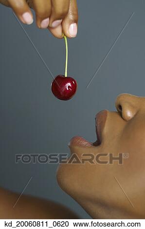Close up of African woman holding cherry over mouth View Large Photo Image Stock Image - Close up of African woman holding cherry over mouth. Fotosearch