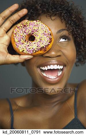 Close up of African woman holding doughnut over eye View Large Photo Image Stock Image - Close up of African woman holding doughnut over eye. Fotosearch