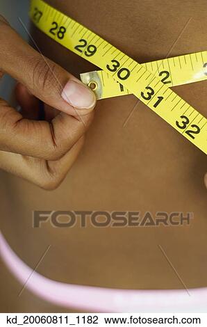 Close up of African woman measuring waist View Large Photo Image Stock Image - Close up of African woman measuring waist. Fotosearch