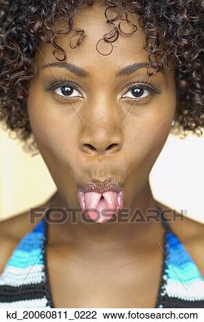 Stock Image - Close up of African woman sticking her tongue out. Fotosearch
