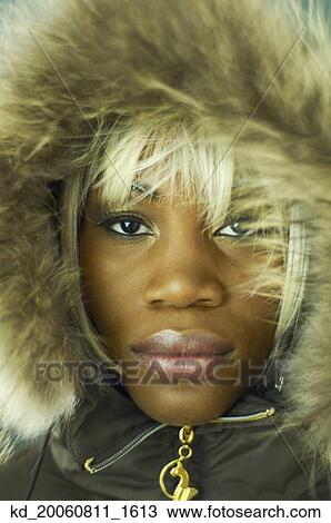 Stock Image - Close up of African woman wearing coat with fur hood. Fotosearch