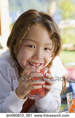 Stock Image - Close up of young Asian girl holding glass of water. Fotosearch