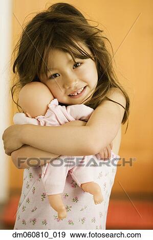 Close up of young Asian girl hugging baby doll View Large Photo Image Stock Photo - Close up of young Asian girl hugging baby doll. Fotosearch