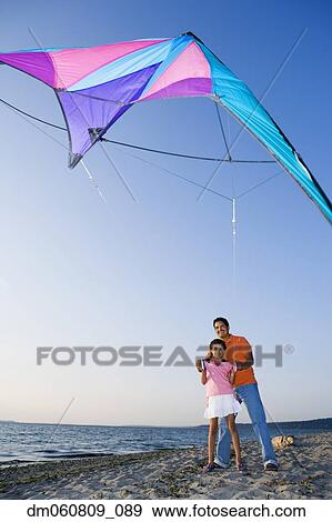 Stock Photo - Father and daughter flying kite at beach. Fotosearch