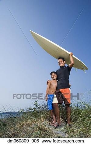 Stock Photograph - Father and son with surfboard on beach. Fotosearch
