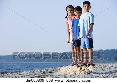 Stock Photo - Hispanic brothers and sister smiling at beach. Fotosearch