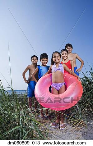 Stock Image - Hispanic children in bathing suits on beach. Fotosearch