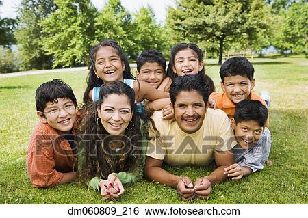 Stock Photograph - Hispanic family laying grass smiling. Fotosearch