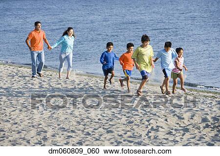 Stock Image - Hispanic family walking on beach. Fotosearch