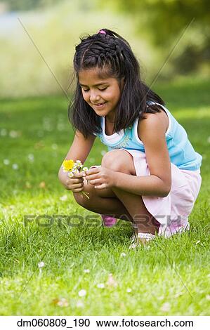 Stock Image - Hispanic girl picking flowers . Fotosearch