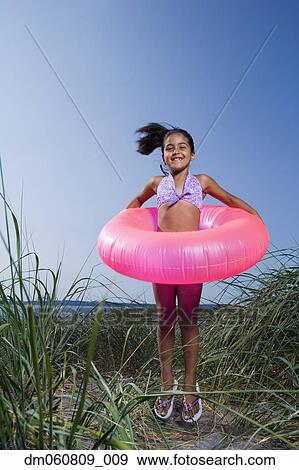 Stock Photo - Hispanic girl smiling with inner tube on beach. Fotosearch
