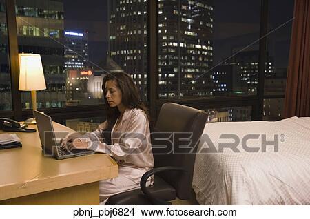Picture - Hispanic woman using laptop in hotel room. Fotosearch