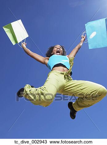 Low angle view of African woman jumping with shopping bags View Large Photo Image Stock Image - Low angle view of African woman jumping with shopping bags. Fotosearch