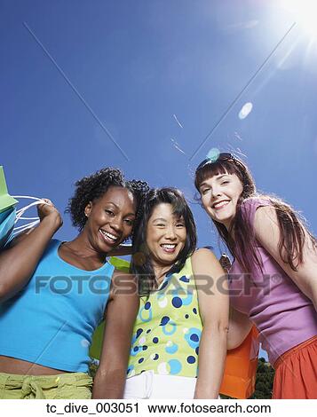 Low angle view of thee women smiling with shopping bags outdoors View Large Photo Image Stock Image - Low angle view of thee women smiling with shopping bags outdoors. Fotosearch