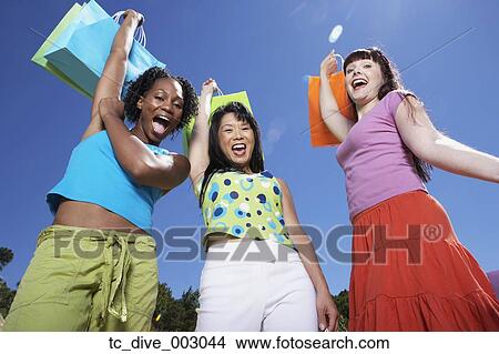 Low angle view of women cheering with shopping bags outdoors View Large Photo Image Picture - Low angle view of women cheering with shopping bags outdoors. Fotosearch