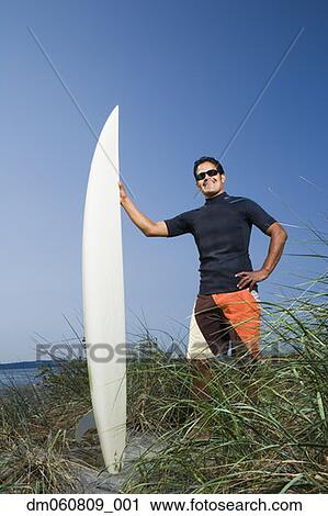 Man holding surfboard and smiling on beach View Large Photo Image Stock Image - Man holding surfboard and smiling on beach. Fotosearch