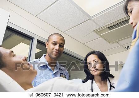 Stock Image - Man in hospital with doctor and paramedics. Fotosearch