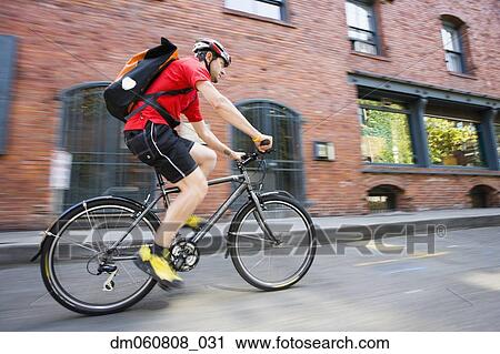 Stock Image - Man riding bicycle on street. Fotosearch