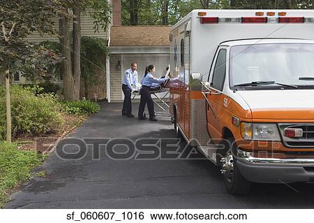 Stock Photograph - Paramedics putting person in ambulance in driveway. Fotosearch