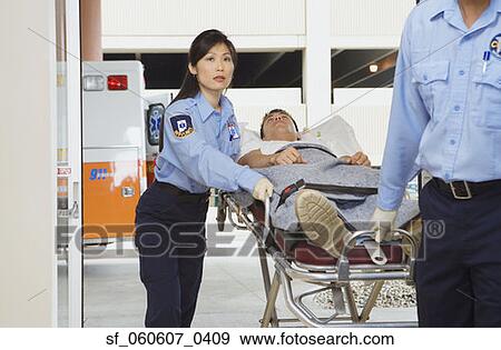 Stock Photo - Paramedics wheeling man into hospital on gurney. Fotosearch
