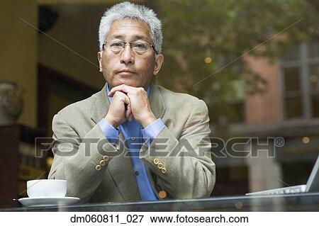 Stock Photo - Senior Asian man with coffee and laptop at cafe. Fotosearch