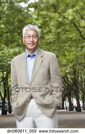 Senior Asian man with hands in pockets at park View Large Photo Image Stock Photo - Senior Asian man with hands in pockets at park. Fotosearch