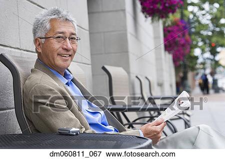 Senior Asian man with reading at outdoor table View Large Photo Image Stock Photo - Senior Asian man with reading at outdoor table. Fotosearch