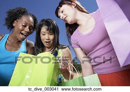 Three woman smiling and looking in shopping bags outdoors View Large Photo Image Stock Image - Three woman smiling and looking in shopping bags outdoors. Fotosearch