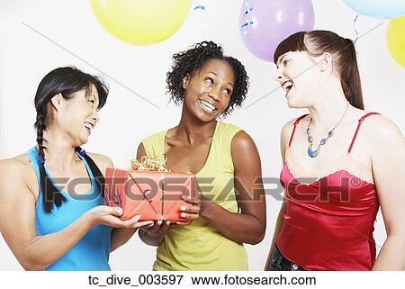 Stock Photo - Three woman smiling with gift and balloons. Fotosearch
