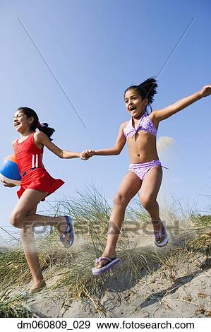 Two Hispanic girls running down dune at beach View Large Photo Image Stock Photo - Two Hispanic girls running down dune at beach. Fotosearch