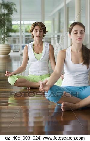 Picture - Two women meditating indoors. Fotosearch