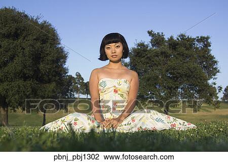 Young Asian woman sitting in grass outdoors View Large Photo Image Stock Image - Young Asian woman sitting in grass outdoors. Fotosearch