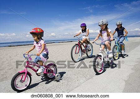 Stock Image - Young girls riding bicycles at beach. Fotosearch