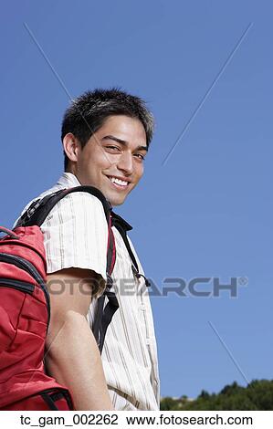 Young man with backpack smiling outdoors View Large Photo Image Stock Image - Young man with backpack smiling outdoors. Fotosearch
