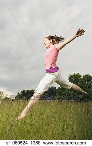 Young woman jumping in meadow View Large Photo Image Stock Photo - Young woman jumping in meadow. Fotosearch